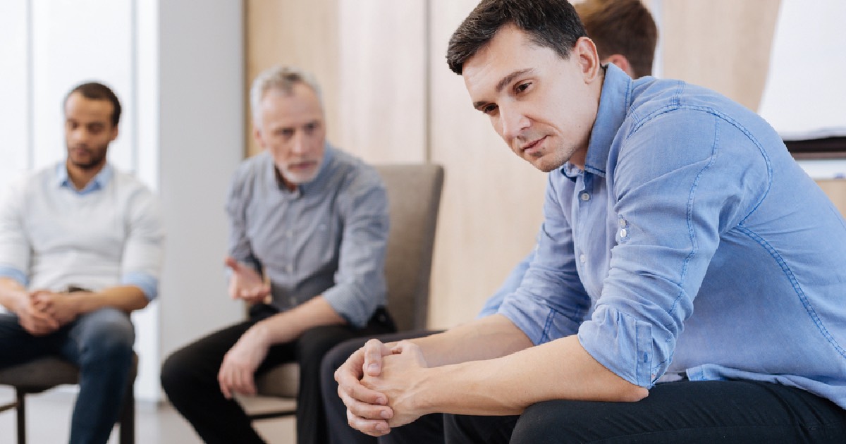 Man sitting in a therapy session with other members