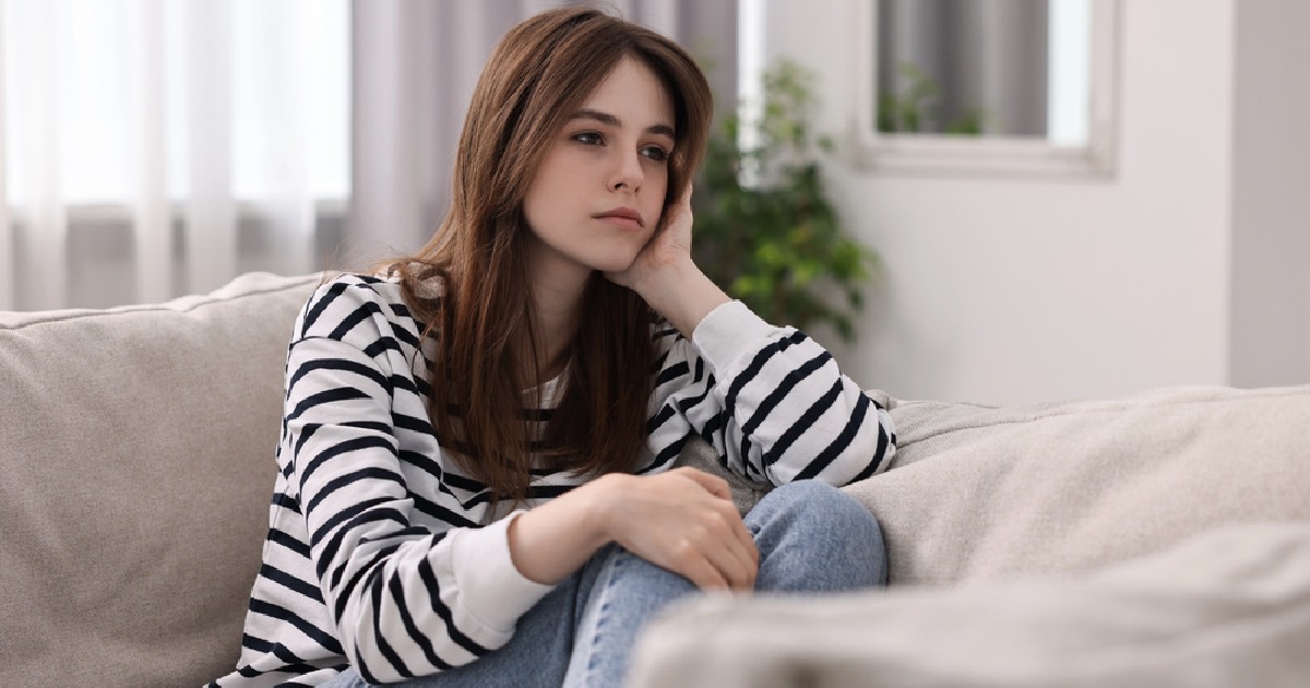 Teenage girl sitting on the couch feeling lonely