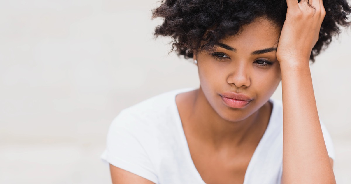 black woman with curly hair holding head