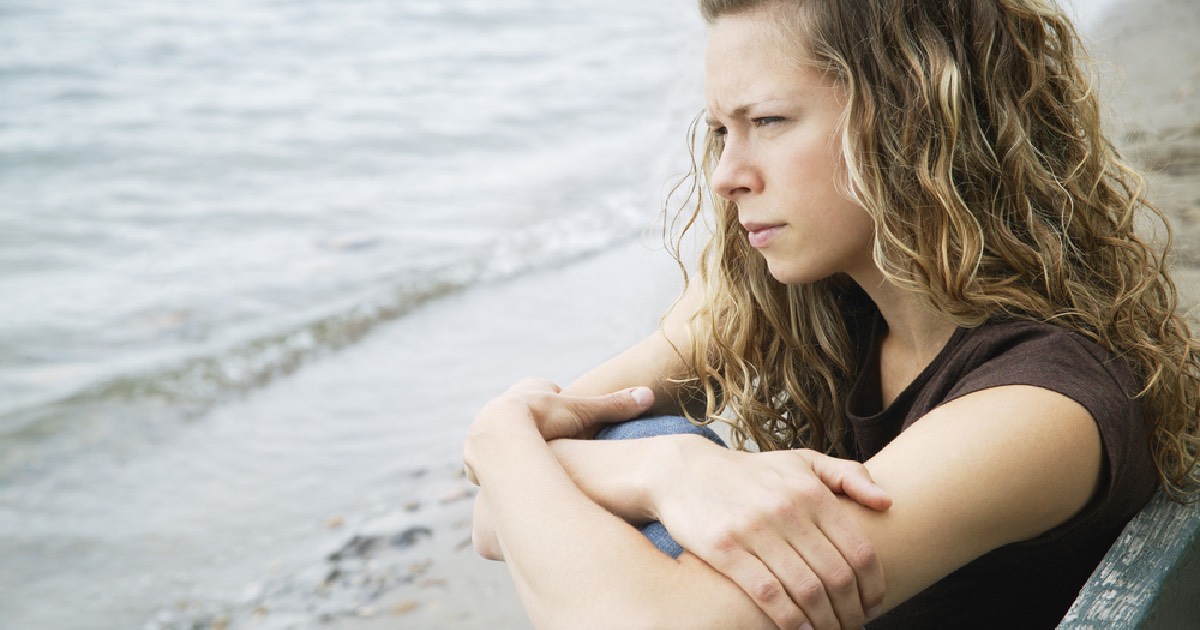 Young female with curly hair sitting on the beach