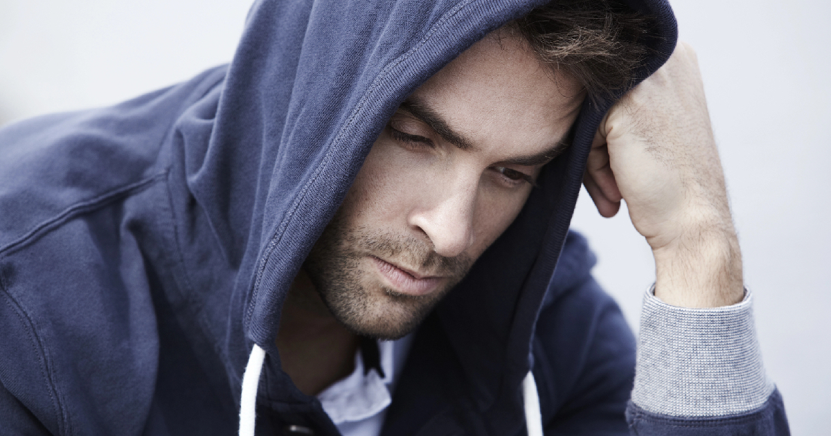 Young man wearing blue hoodie looking sad