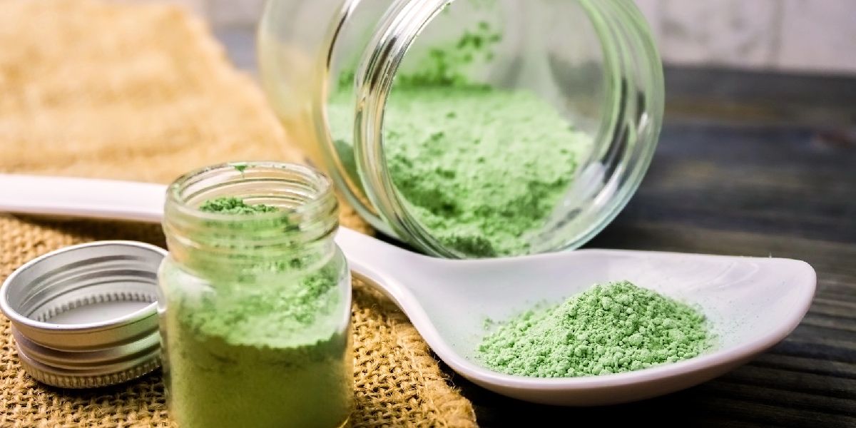 Green kratom powder with spoon and jar